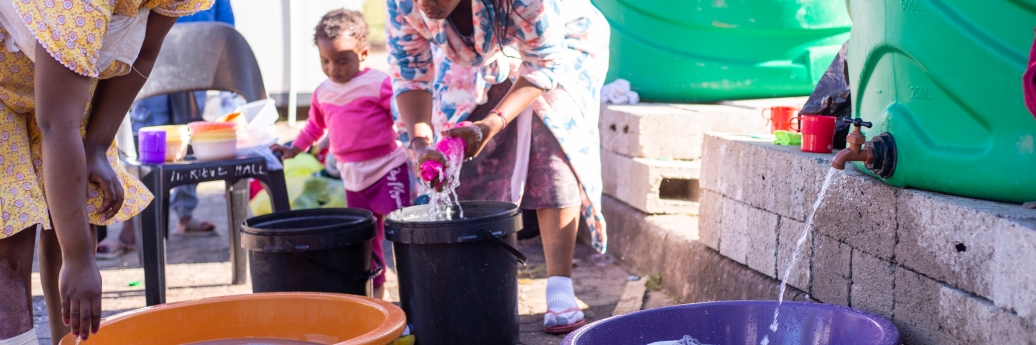 vrouwen in Zuid-Afrika nemen water uit een ton